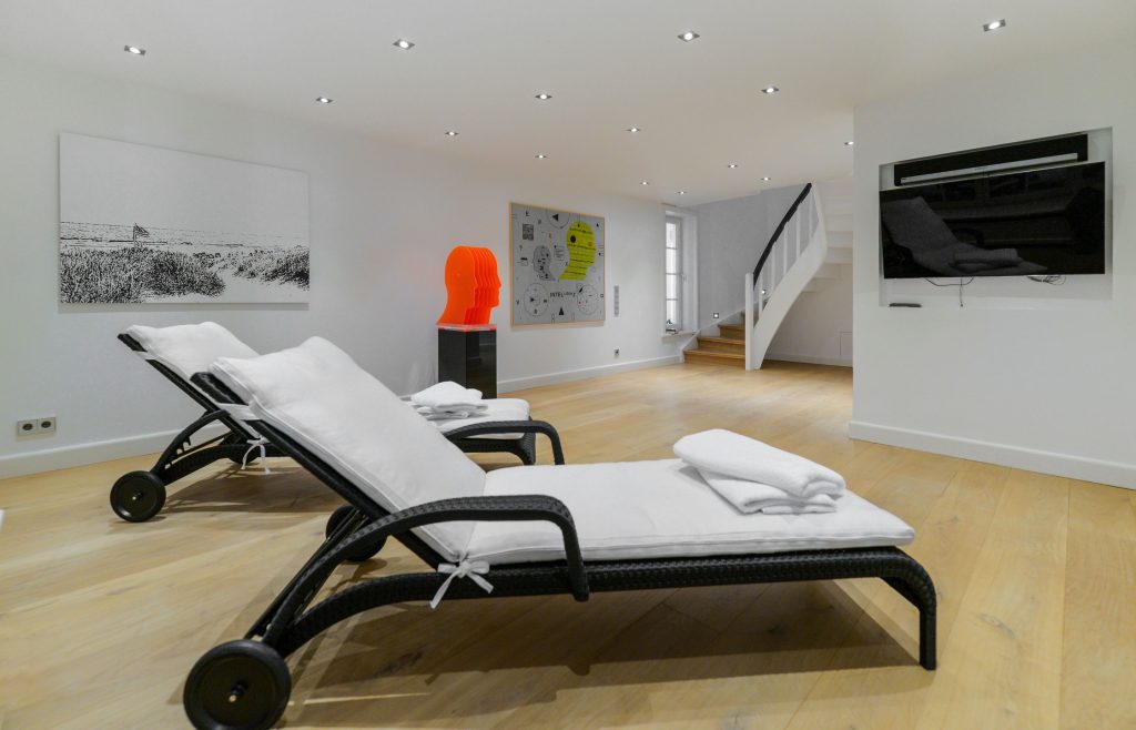 Ästethisch schöner Wellnessraum mit Kunstwerken an der Wand und auf einem Podest in einem Ferienhaus auf Sylt