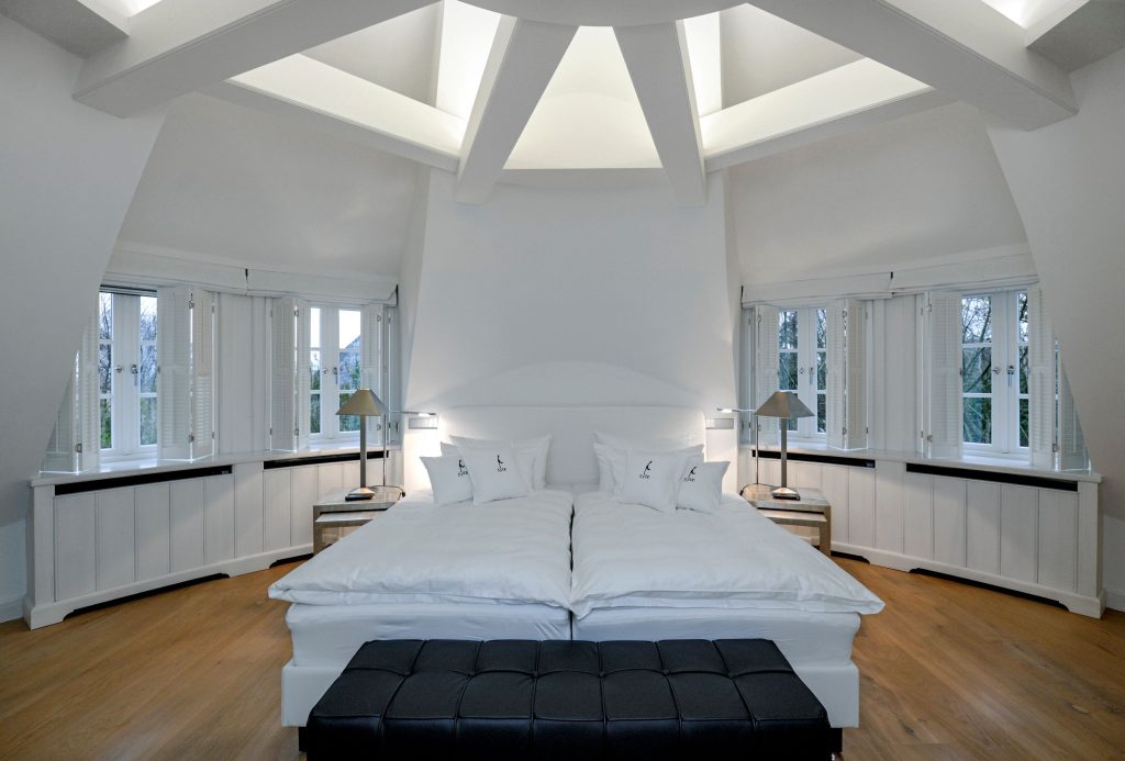 Elegantes weißes Schlafzimmer in einem runden Dachausbau in einem Ferienhaus auf Sylt