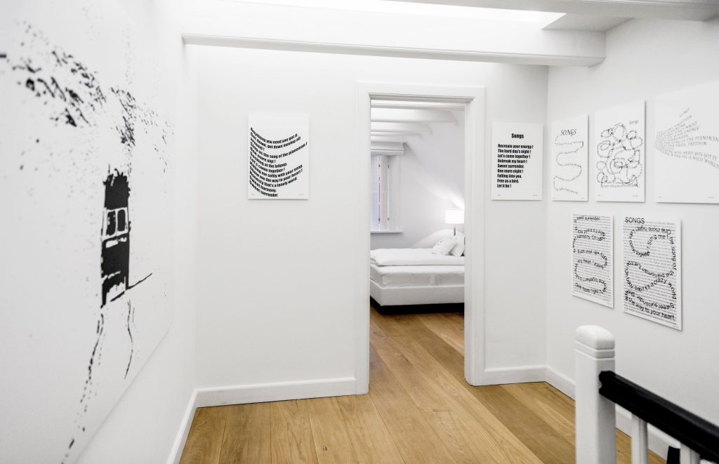 Flur von einem Ferienhaus auf Sylt in einem modernen, weißen Stil mit diversen schwarz weißen Kunstwerken