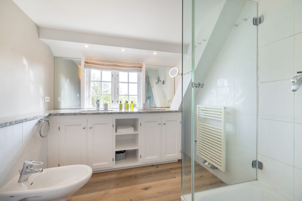 Badezimmer mit Dusche und zwei Waschbecken in Ferienwohnung in Keitum