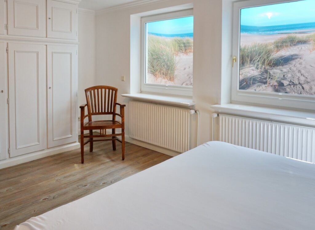 Doppelbett mit Holzstuhl in Ferienwohnung in Keitum